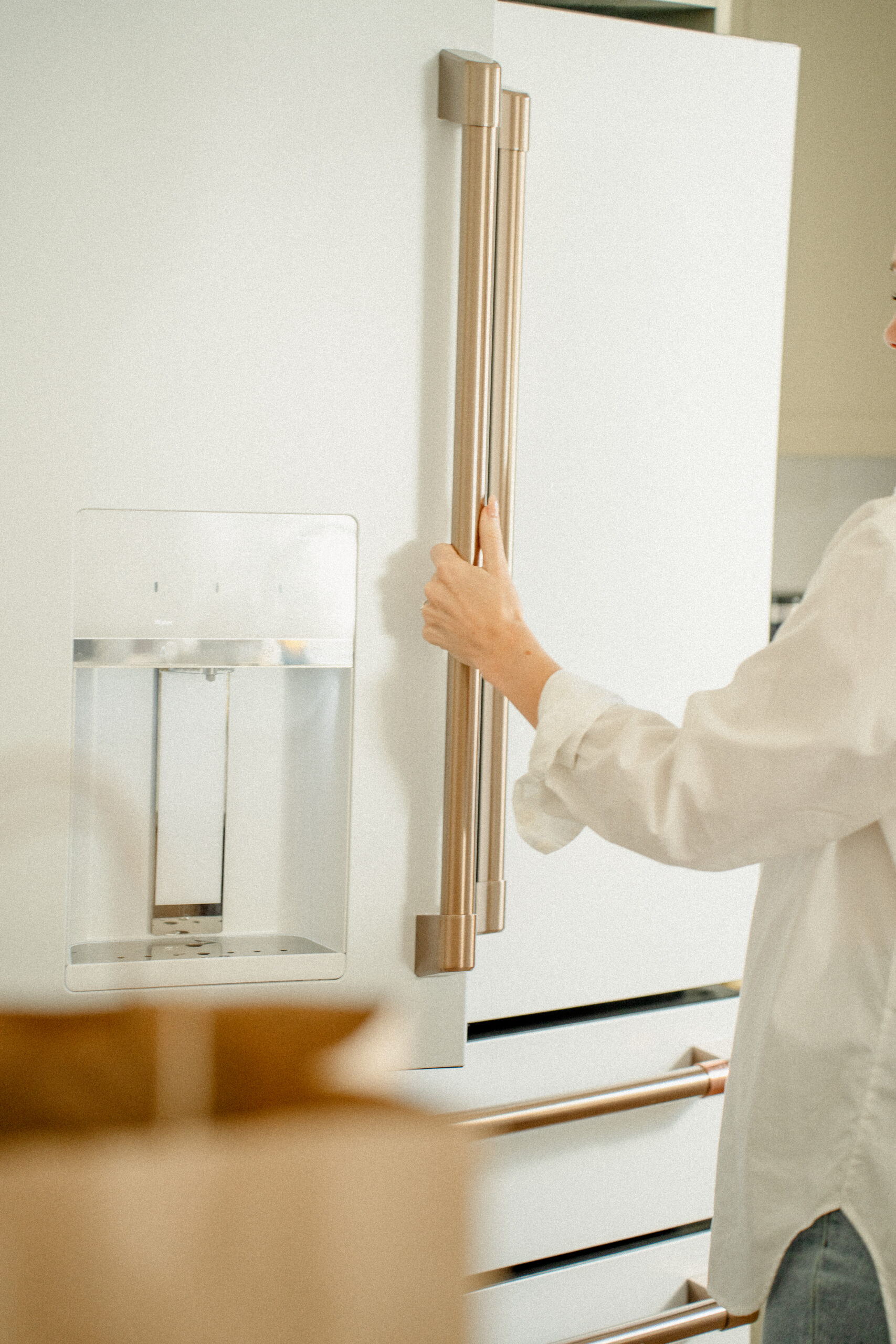 Person opening a modern refrigerator in a calm, neutral kitchen designed for functionality and reduced cognitive load.